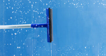 Rubber squeegee cleans window. Clears a stripe of soaped window. Cleaning service concept.
